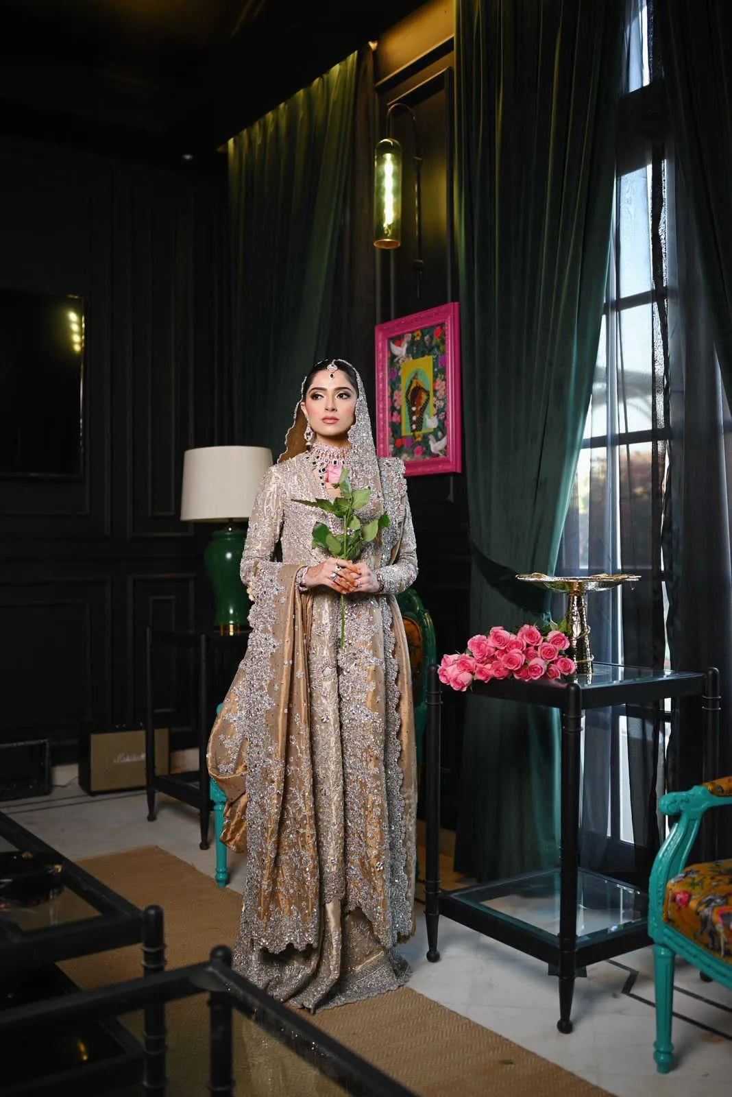 Woman in a patterned dress standing in a room with green curtains and decorative elements.