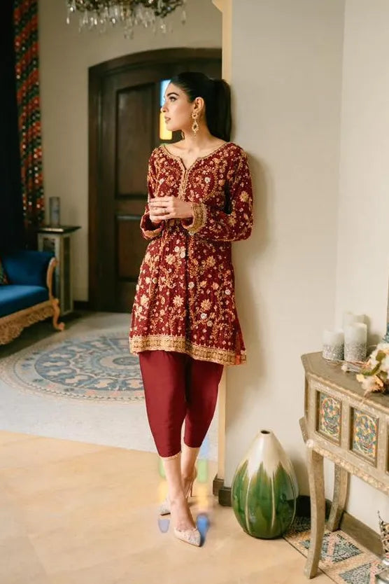 Woman in a red patterned dress standing in a decorated room with a chandelier.