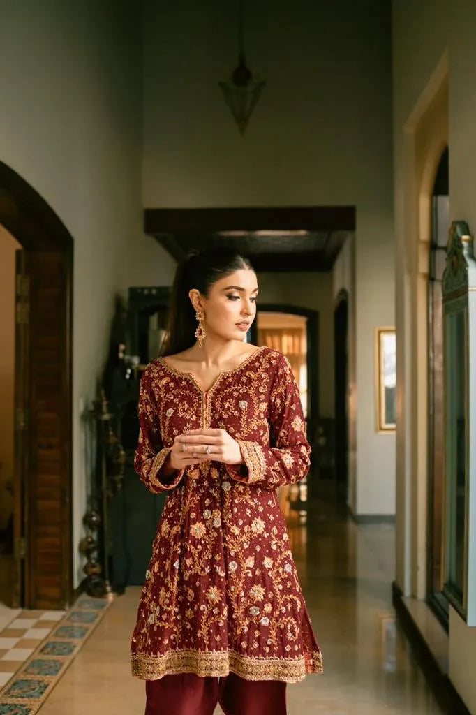Woman in a maroon floral dress standing in a hallway
