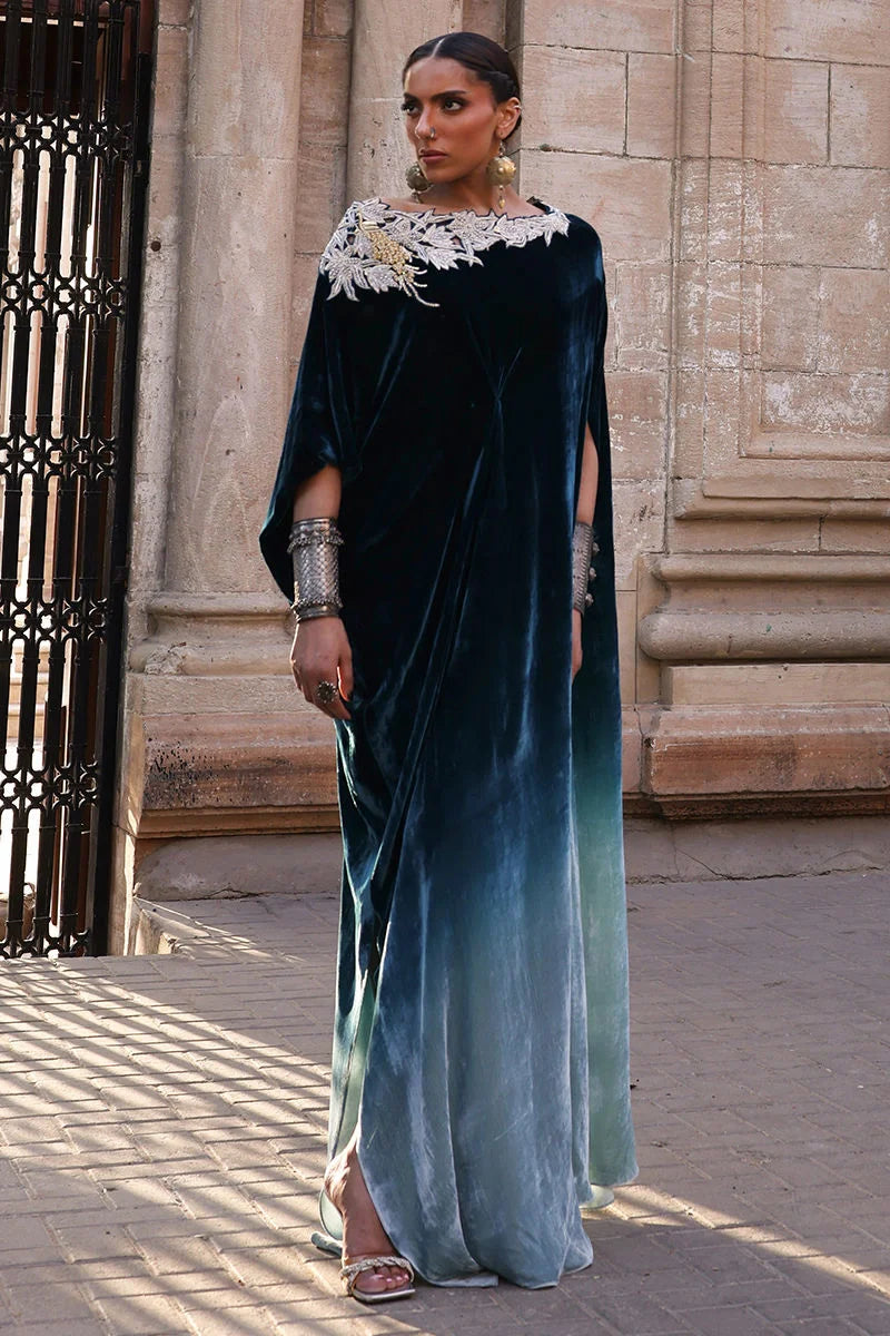 Woman wearing a blue and green gradient dress with white lace details in an urban setting.