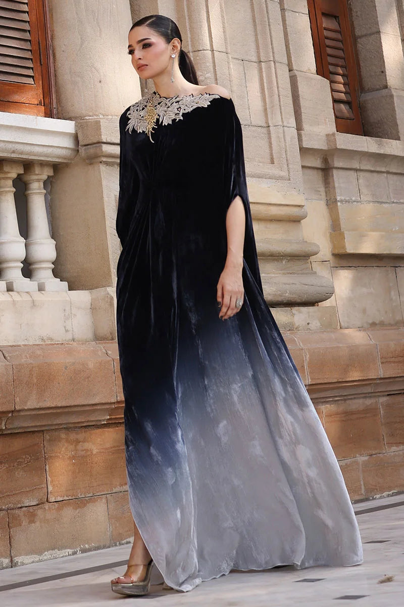 Woman wearing a black and gray gradient dress in front of a stone building.