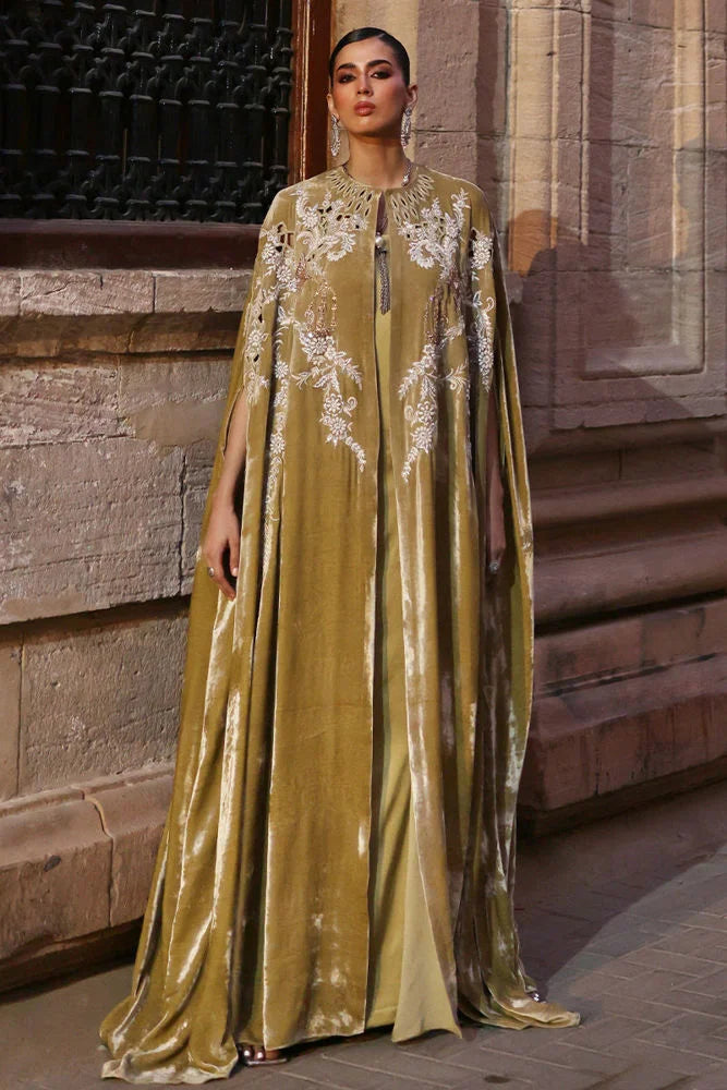 Woman wearing a long, elegant dress with floral patterns in front of a stone building.