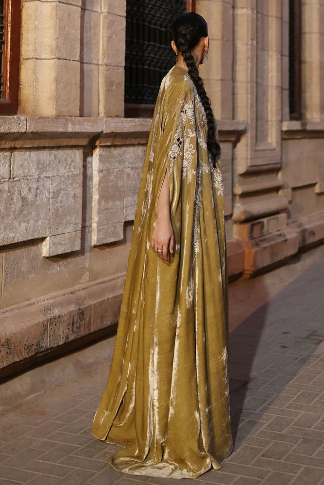 Woman in a long, gold dress standing in front of a stone building.