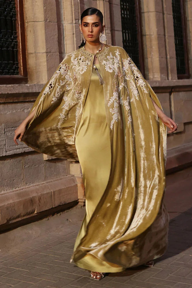 Woman in a long, elegant dress with a cape standing outdoors.