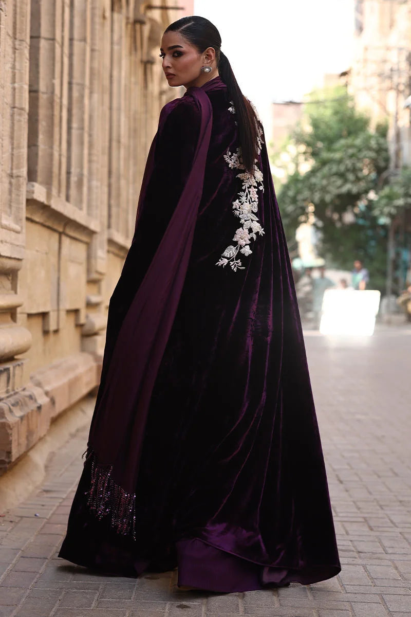 Woman wearing a dark purple velvet dress with floral embellishments on a city street.
