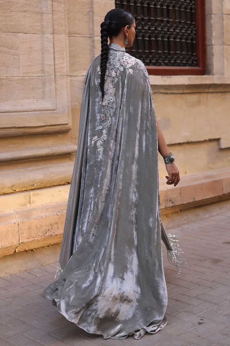 Woman in a long, flowing silver dress walking outdoors.