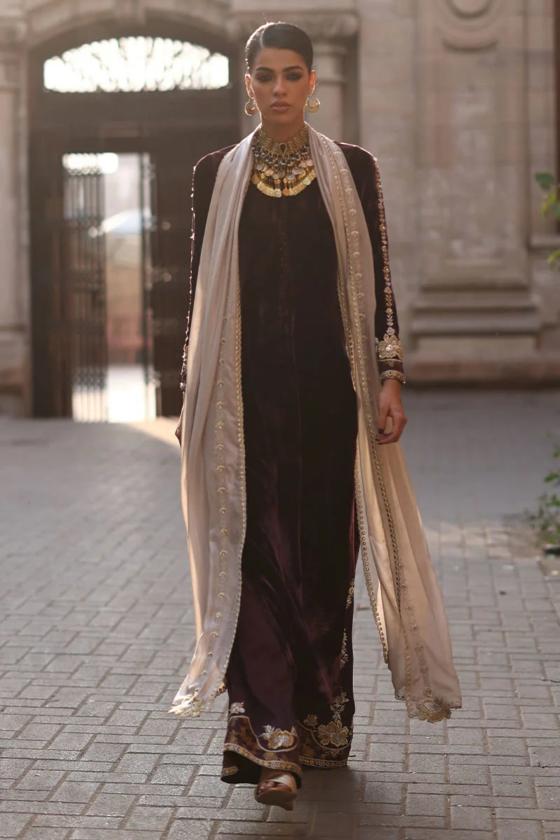 Woman in traditional outfit with long scarf walking on a street.