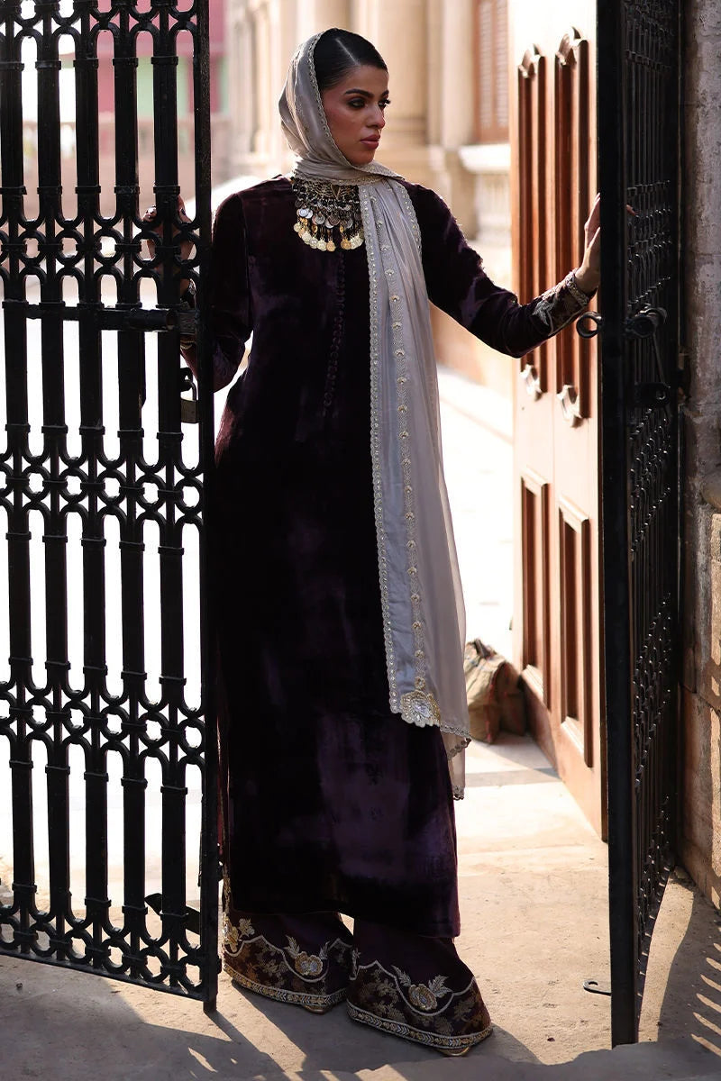 Woman in traditional attire standing in front of a decorative metal gate.