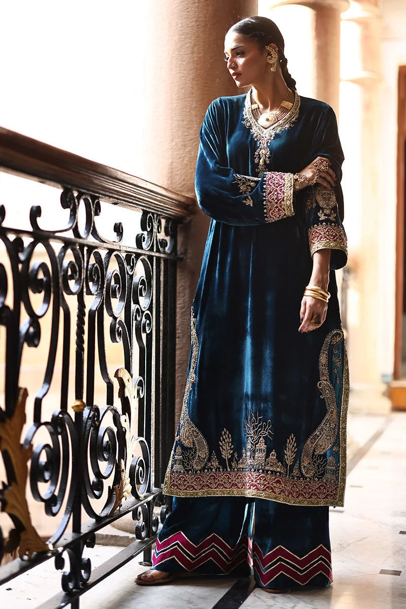 Woman in a traditional blue and gold outfit standing on a balcony.