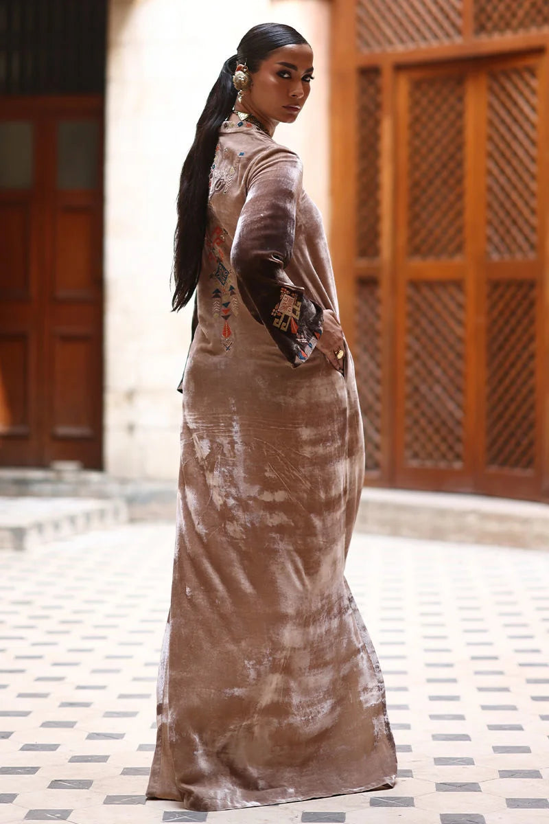 Woman in a long, patterned dress standing outdoors with wooden lattice in the background