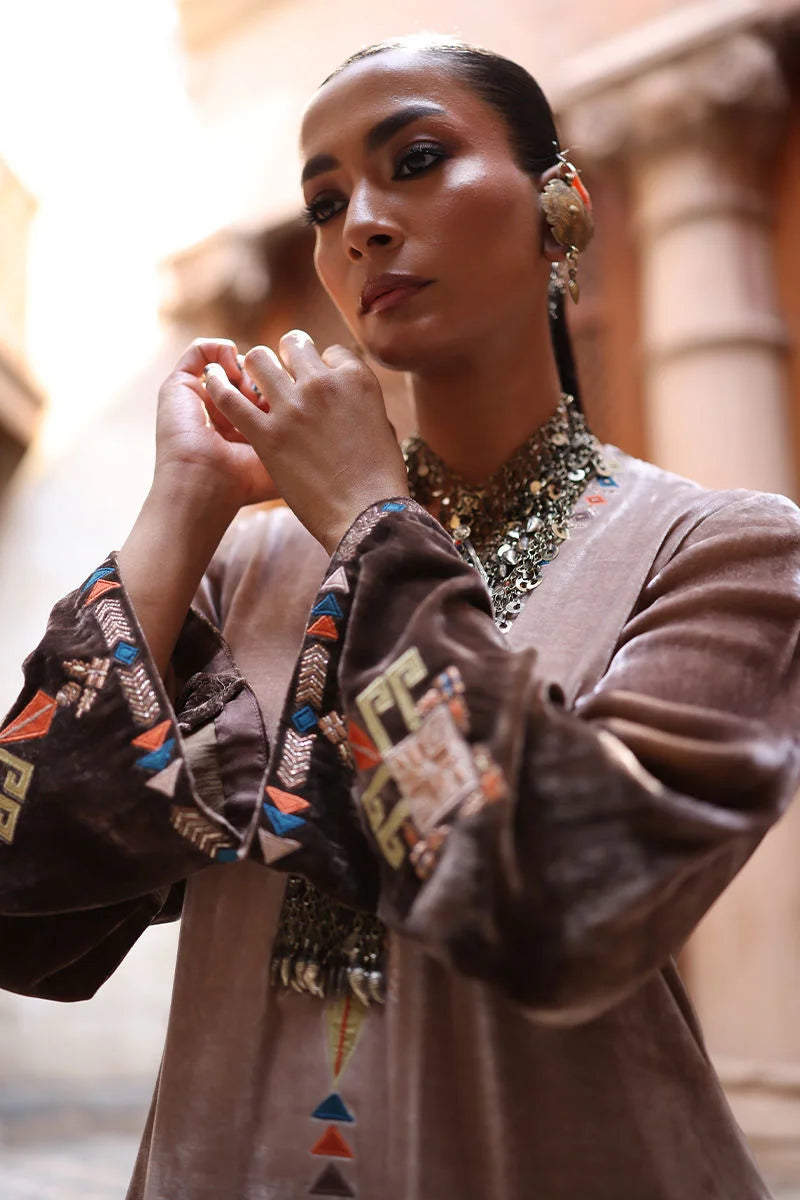 Woman wearing traditional attire with intricate patterns and jewelry, standing outdoors.