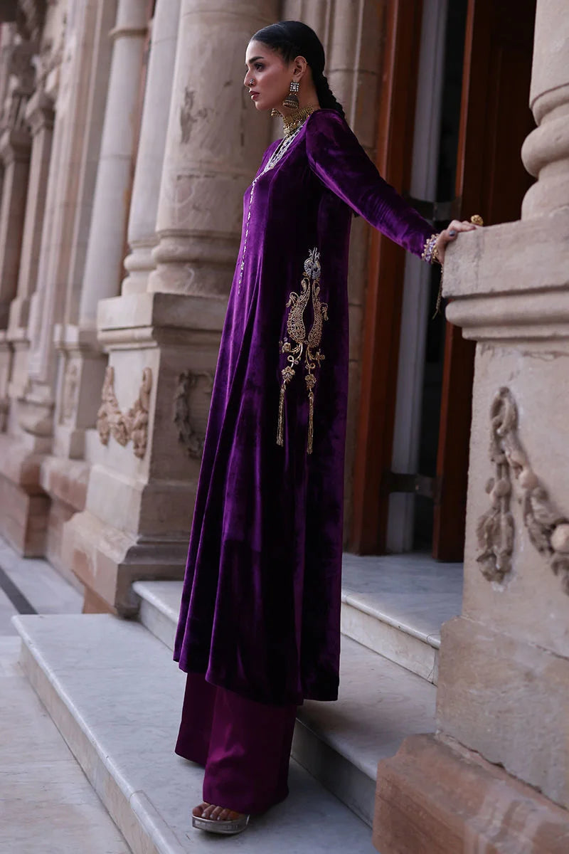 Woman in a purple traditional outfit standing against an architectural background