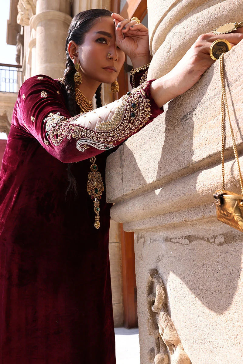 Woman in traditional attire standing next to a stone sculpture with intricate details.