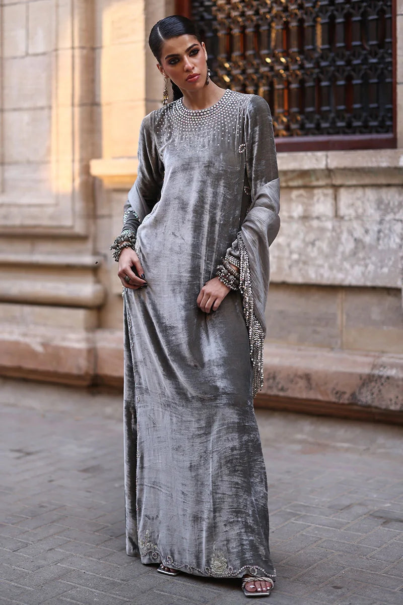 Woman in a long, elegant silver dress standing in front of a stone building.