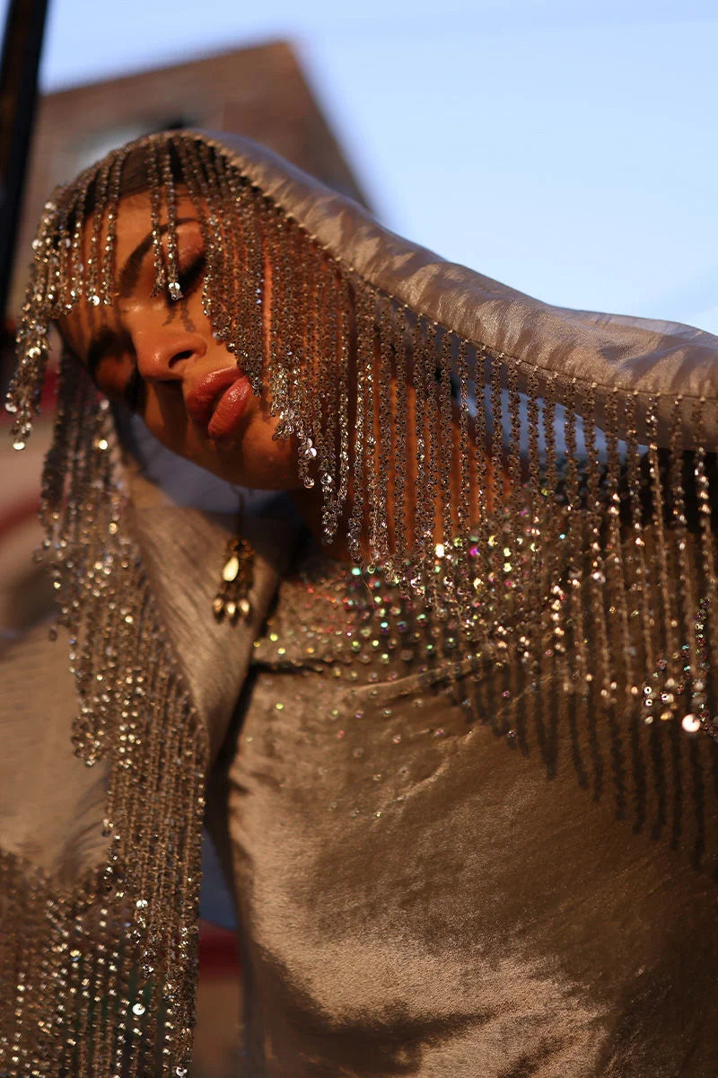 Person wearing a sparkling silver outfit with fringe details.