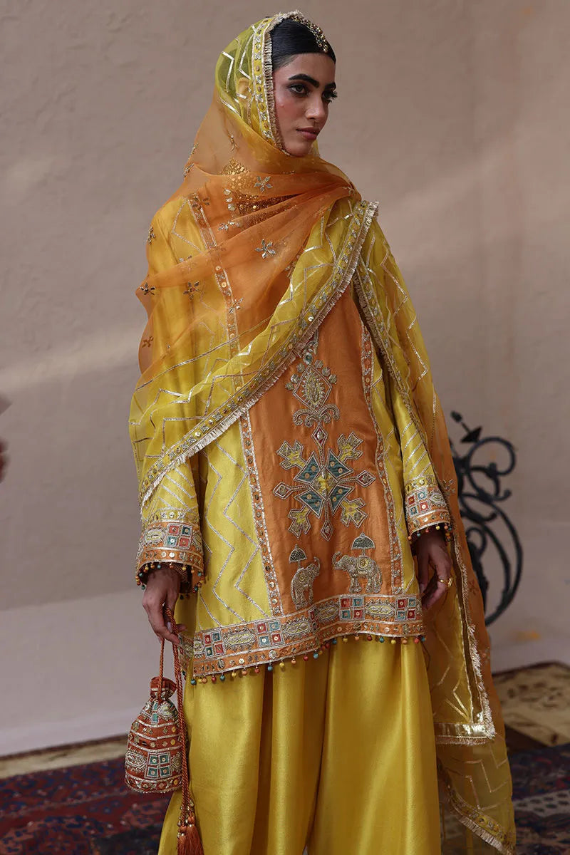 Woman wearing a traditional embroidered yellow outfit with a matching headscarf.