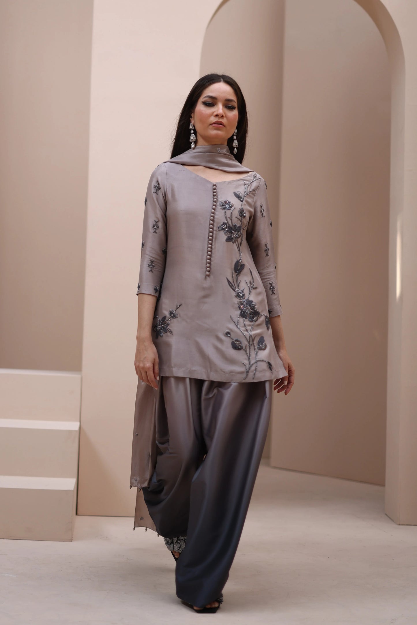 Woman wearing a gray floral outfit in a neutral setting