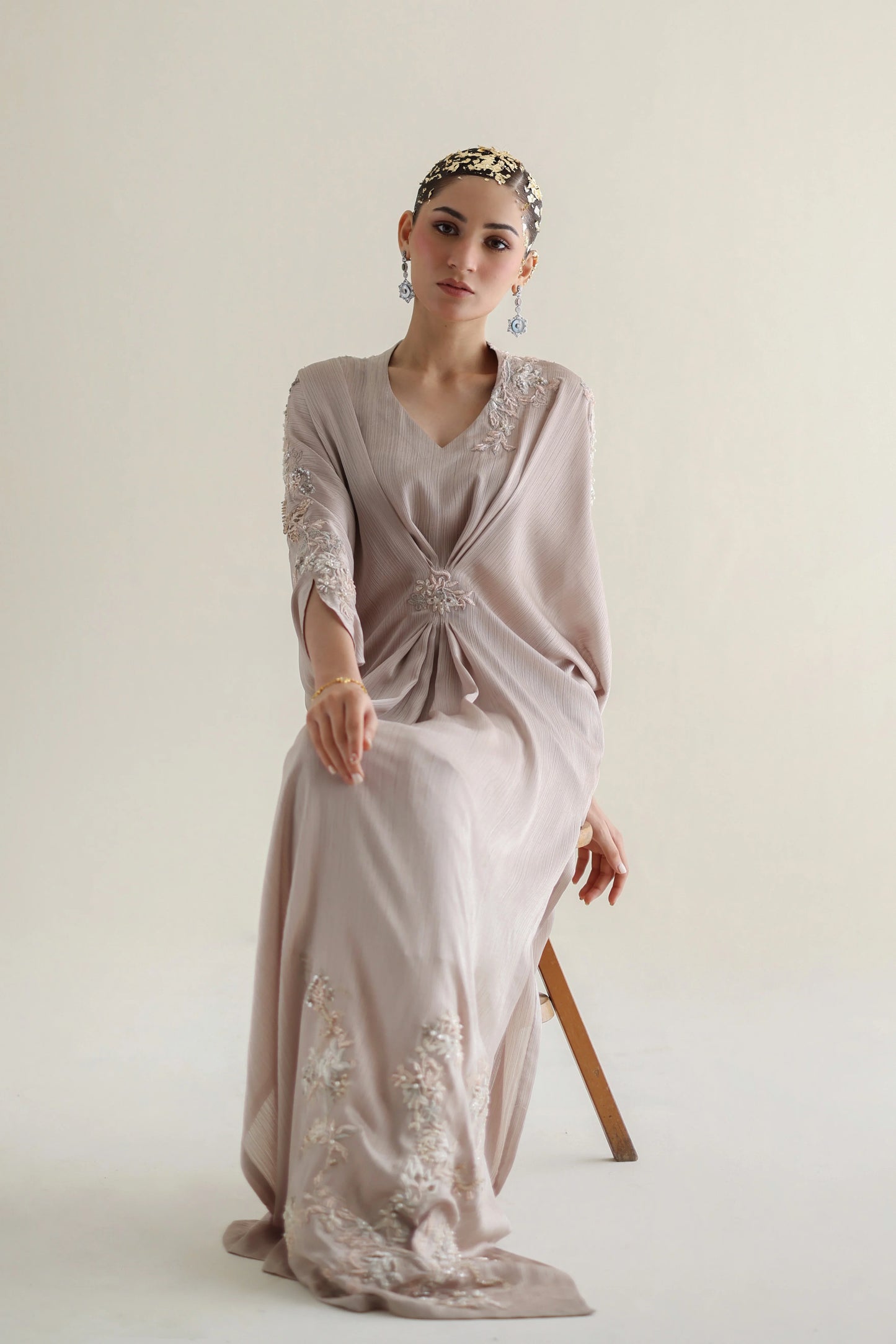 Woman wearing a light pink dress with floral embroidery on a white background