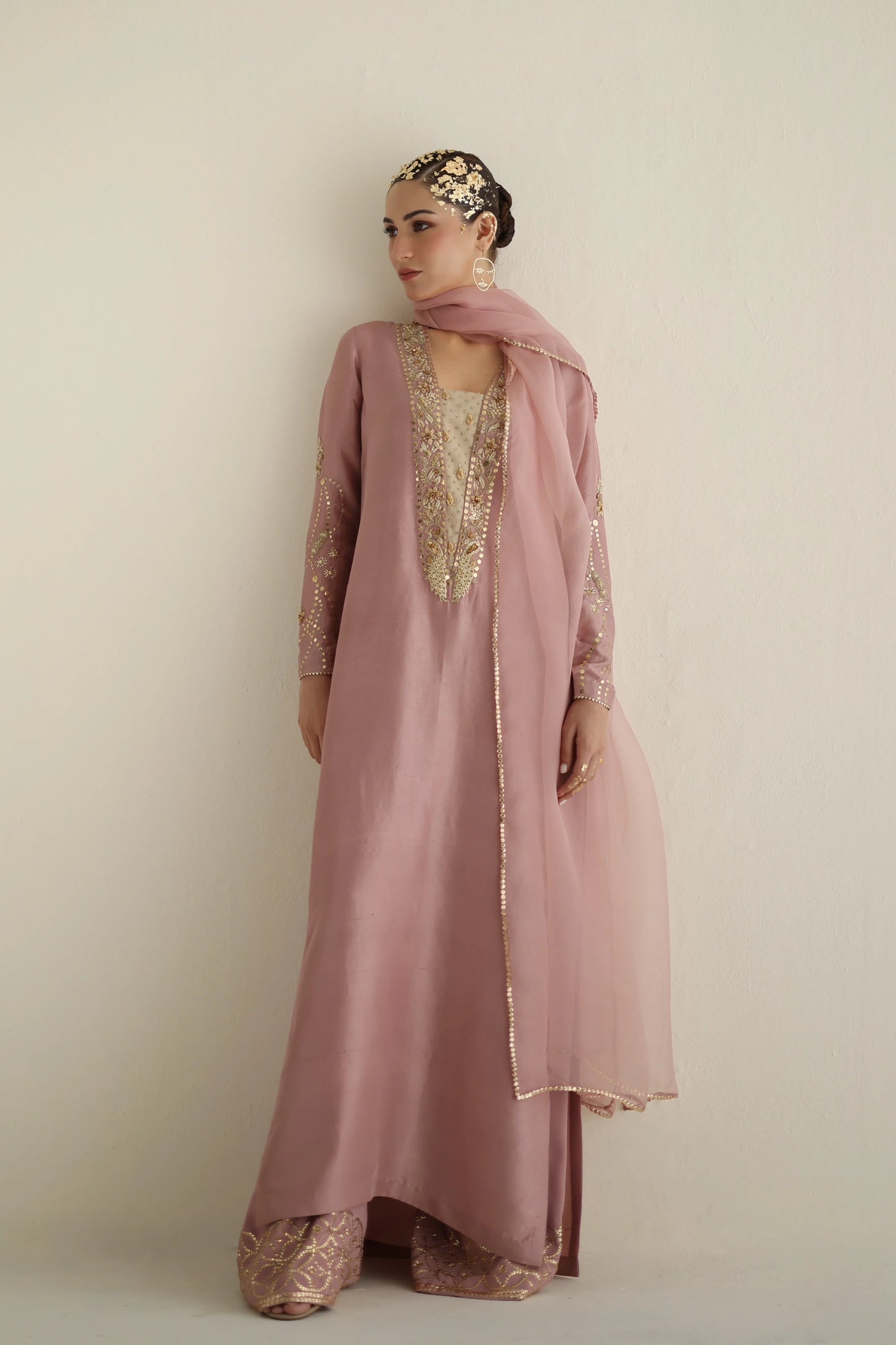 Woman wearing a pink embroidered outfit with a beige background
