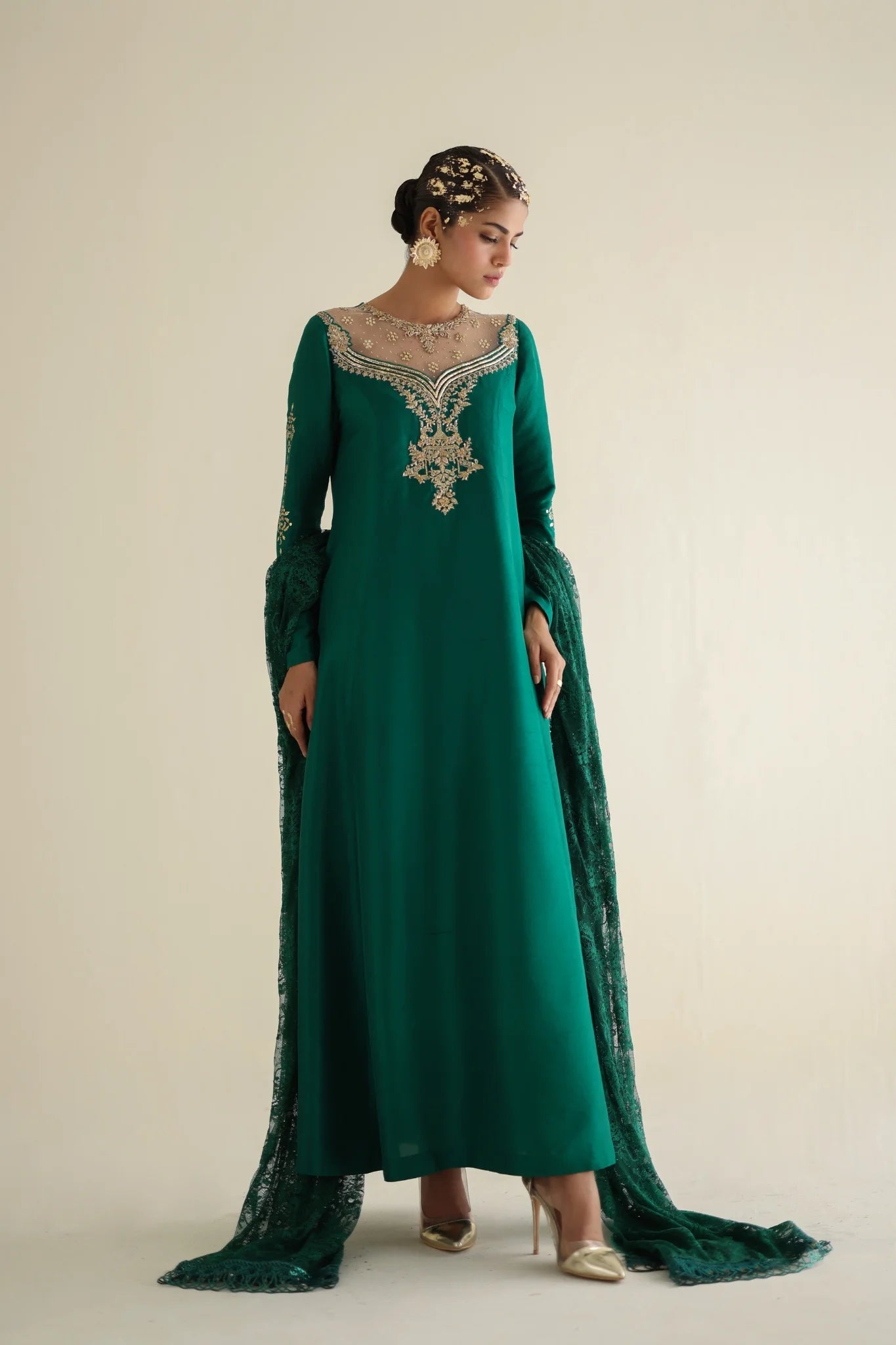 Woman wearing a green embroidered dress with a plain background