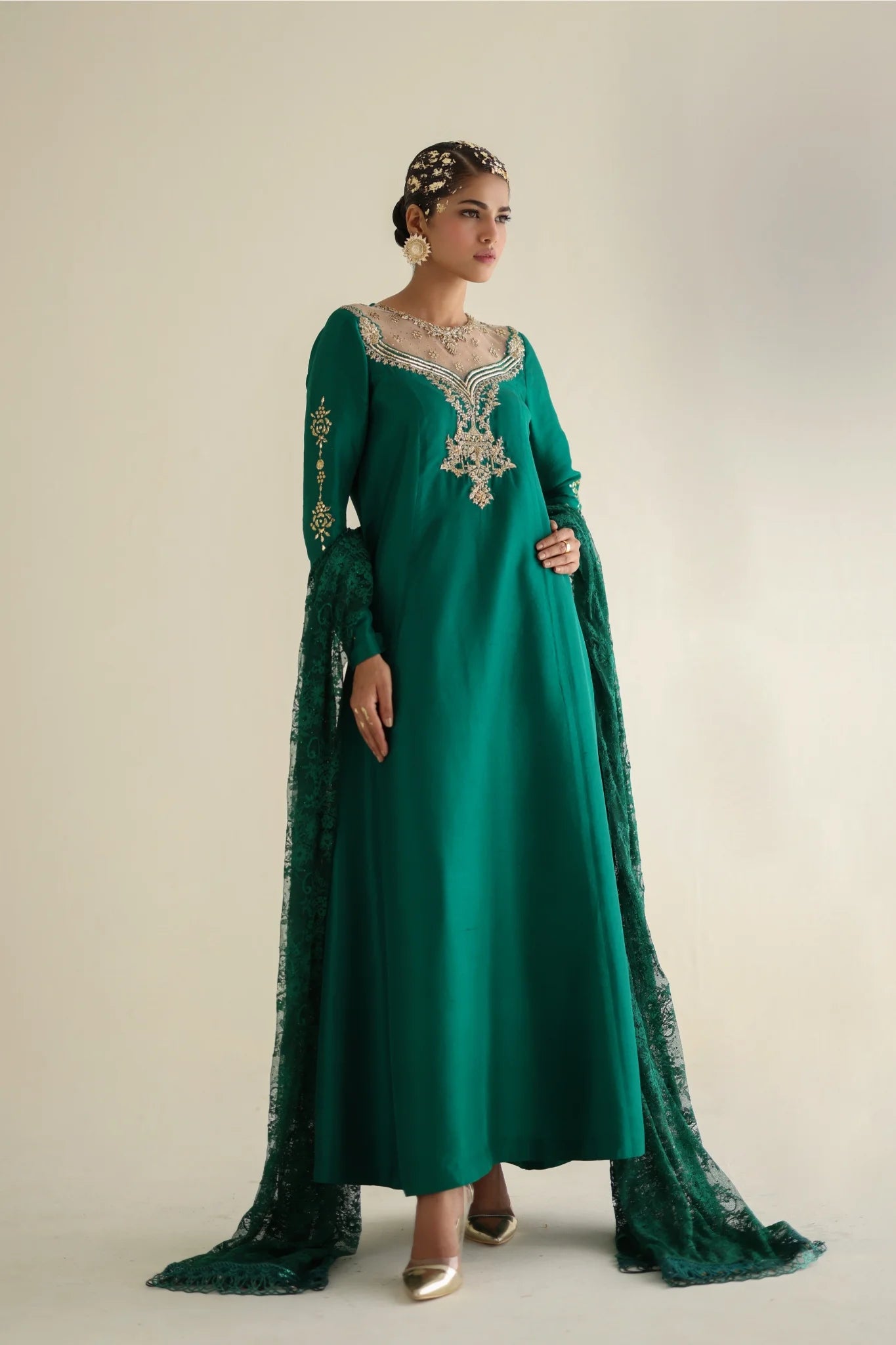Woman wearing a green embroidered dress with a matching dupatta on a plain background
