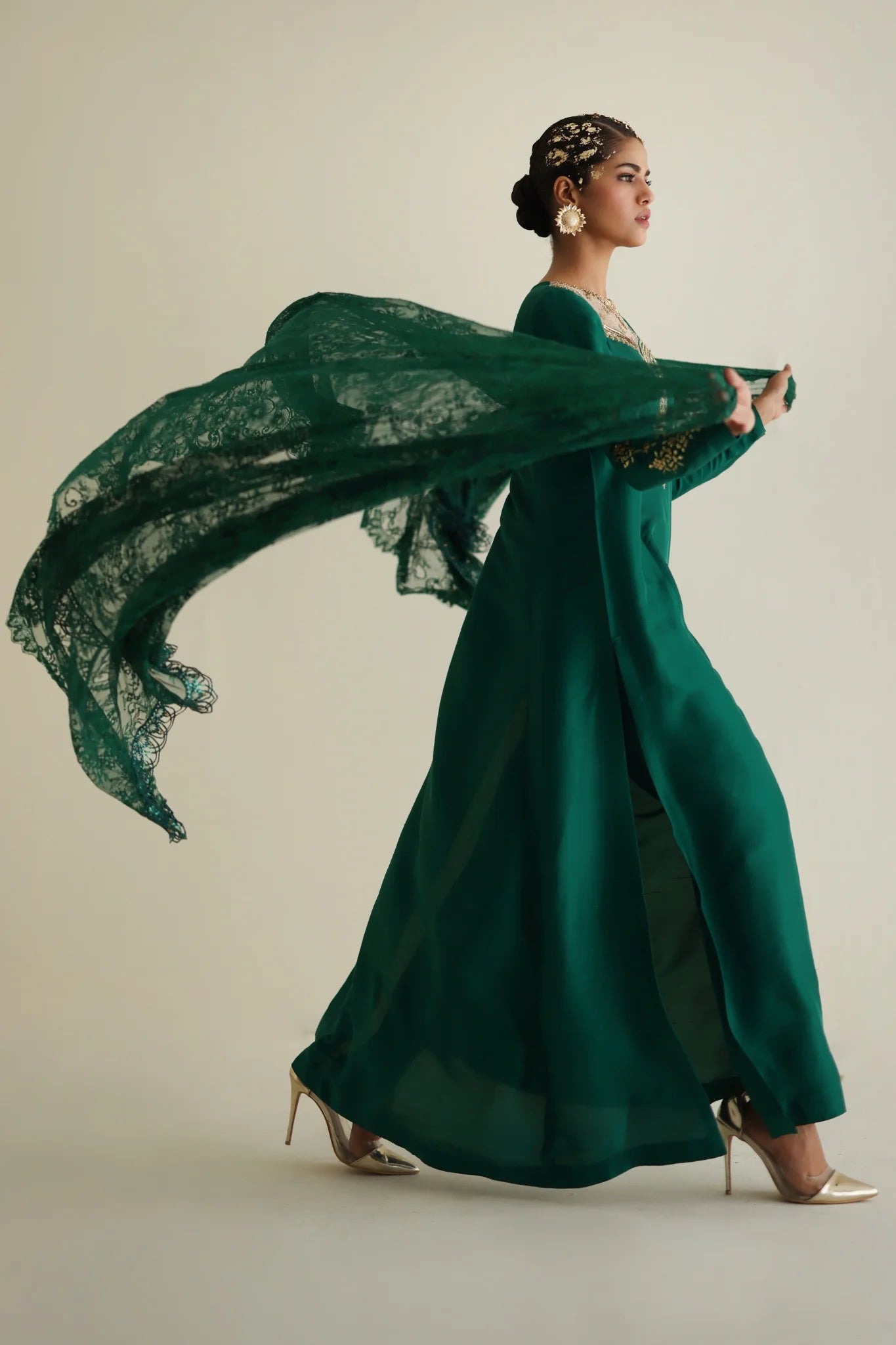 Woman in a long green dress with a flowing fabric against a neutral background