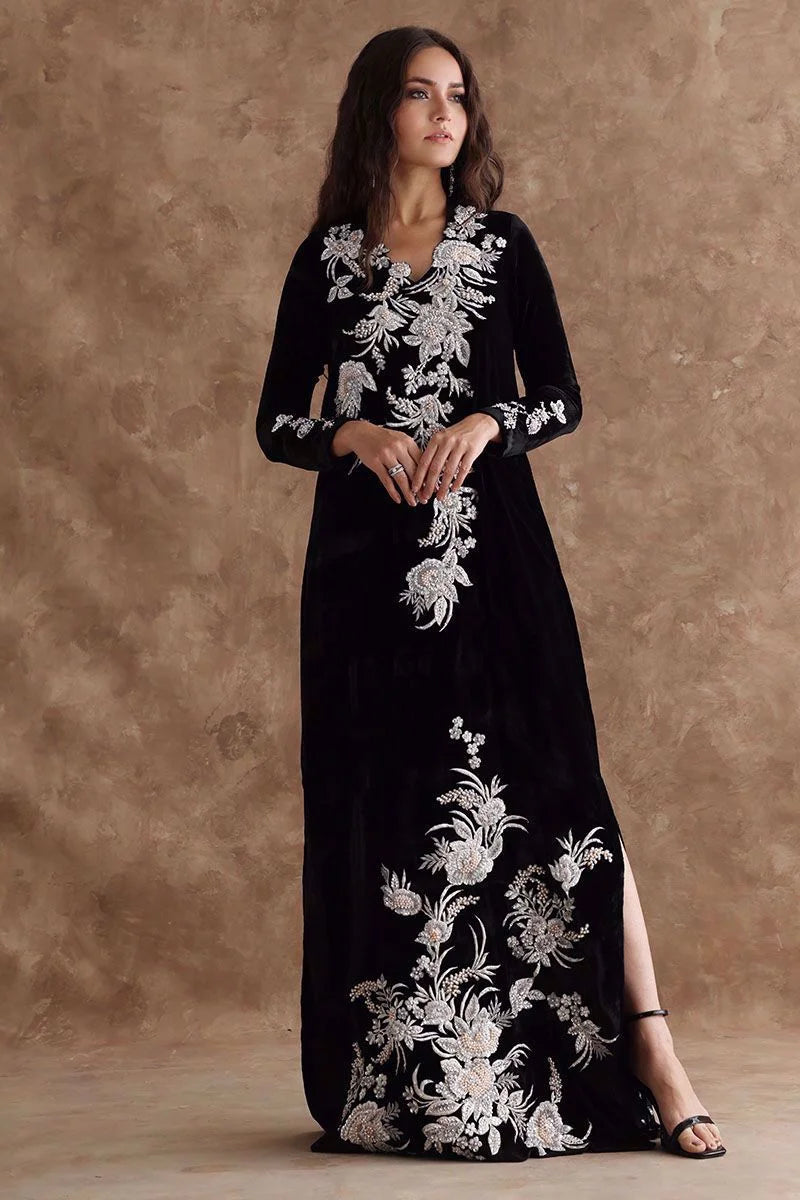 Woman wearing a black dress with white floral embroidery against a brown background