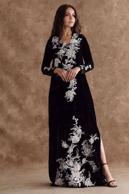 Woman wearing a black dress with white floral embroidery against a brown background