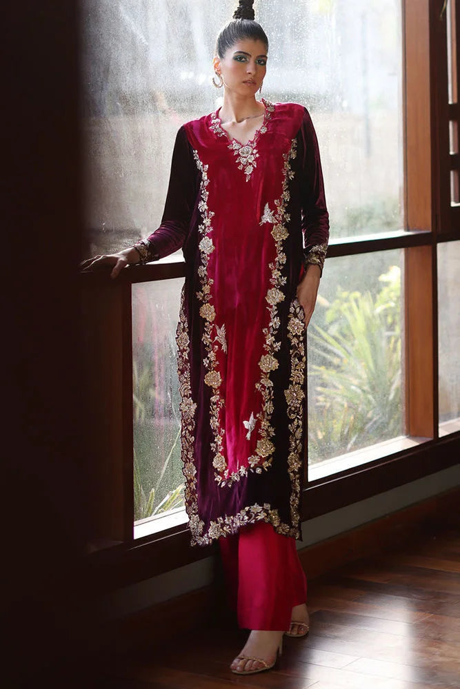 Woman in a traditional outfit standing by a window with a garden view