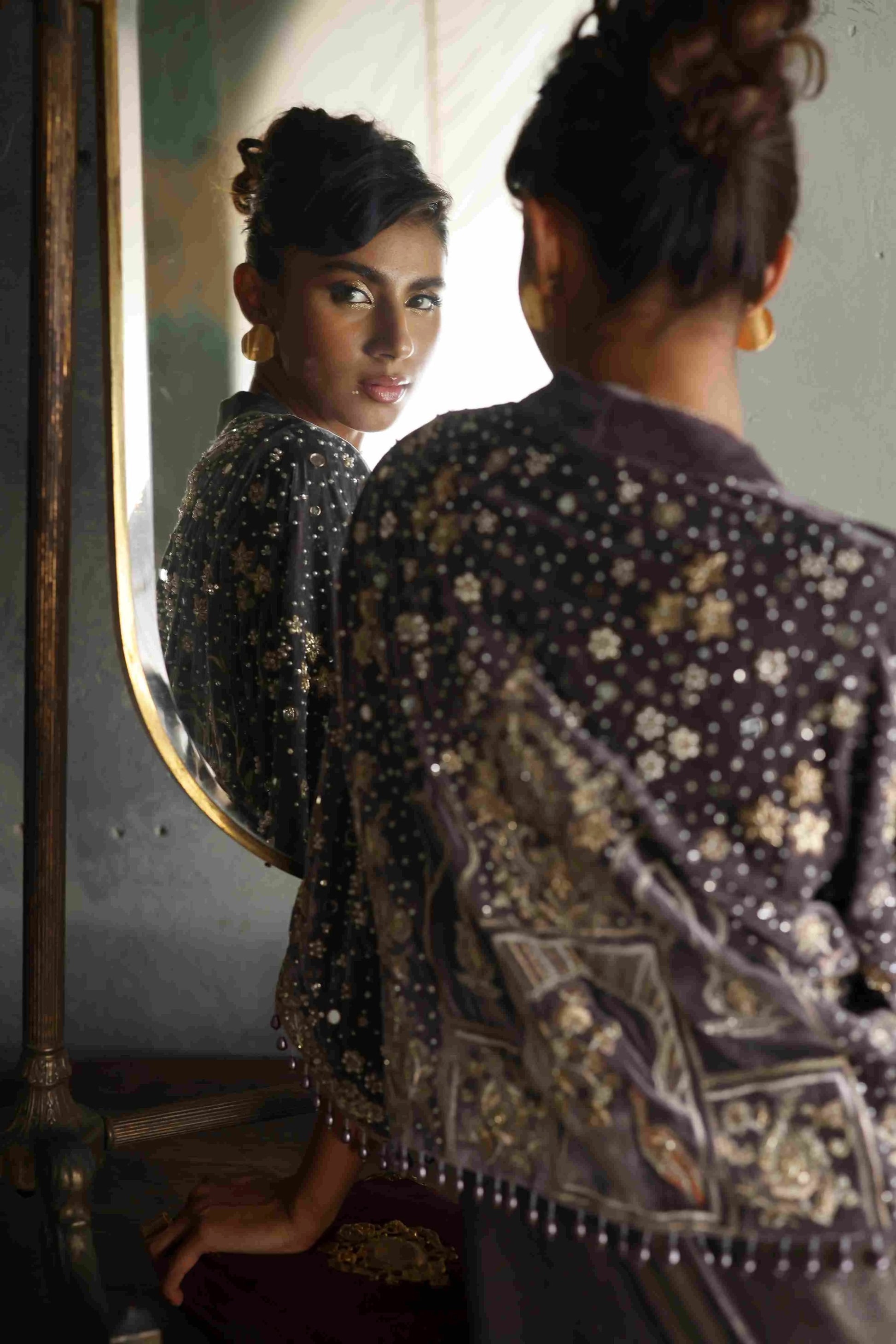Woman in a patterned outfit looking at herself in a mirror.