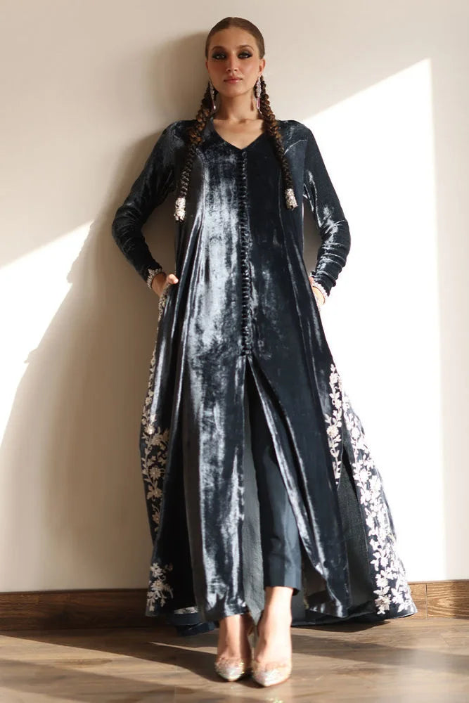 Woman wearing a long, dark blue dress with floral patterns indoors.