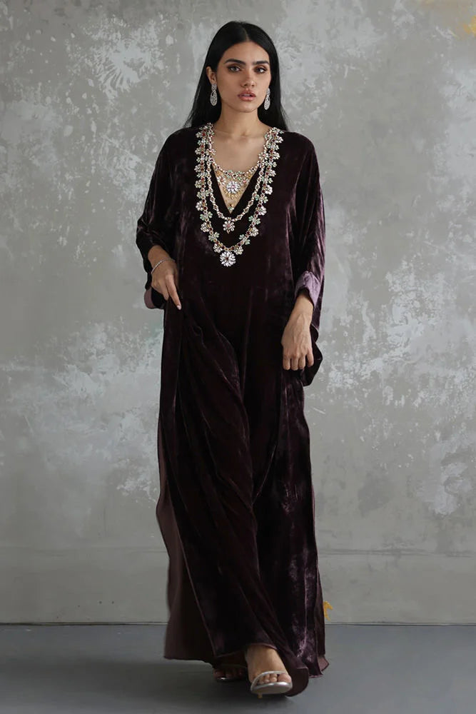 Woman wearing a dark purple velvet dress with a textured gray background