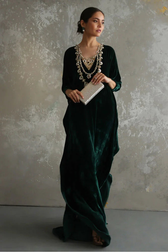 Woman in a dark green saree with a textured wall background