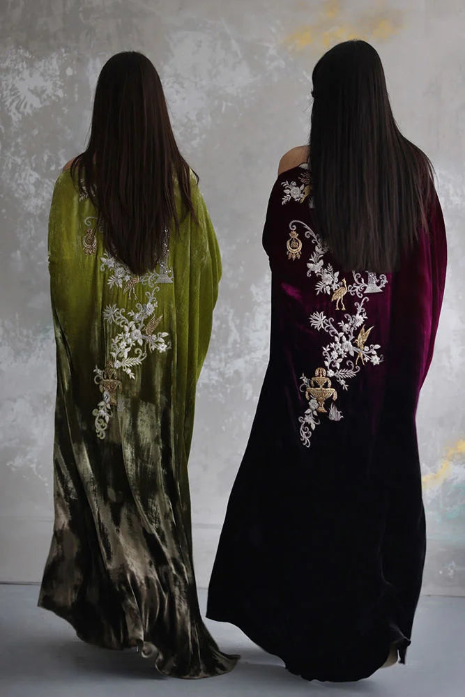 Two women wearing long, embroidered dresses with a neutral background