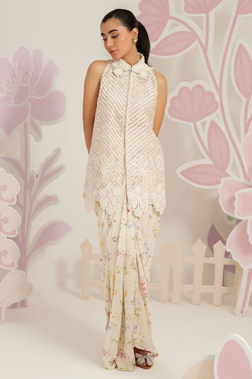 Woman wearing a cream-colored dress with floral patterns against a floral background