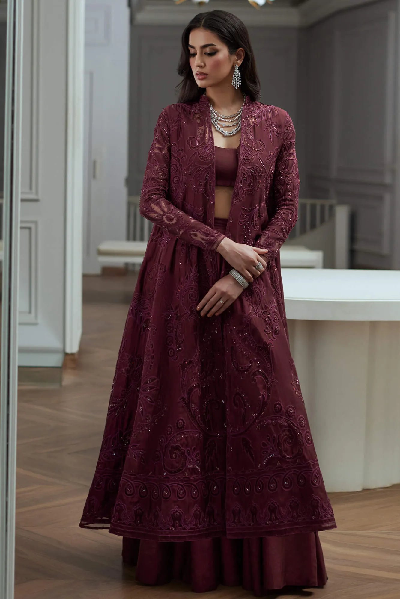 Woman wearing a burgundy embroidered dress and jacket in an indoor setting.