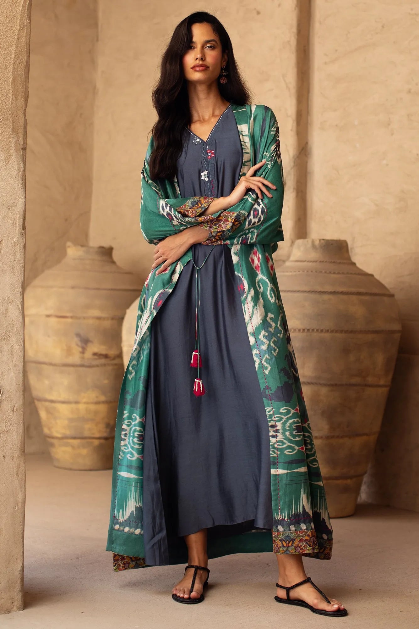 Woman wearing a long, patterned dress with a beige background