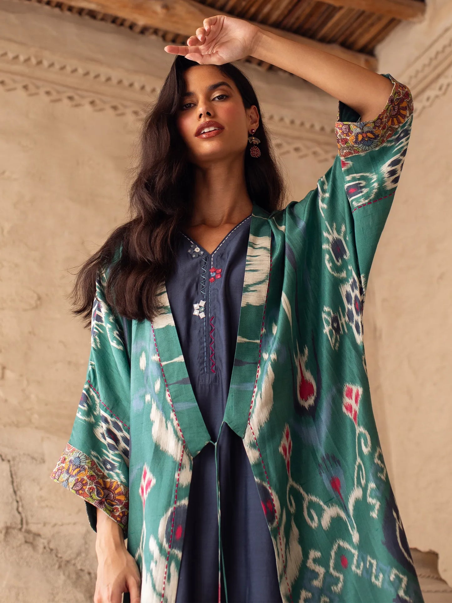 Woman wearing a green patterned kimono-style garment indoors.