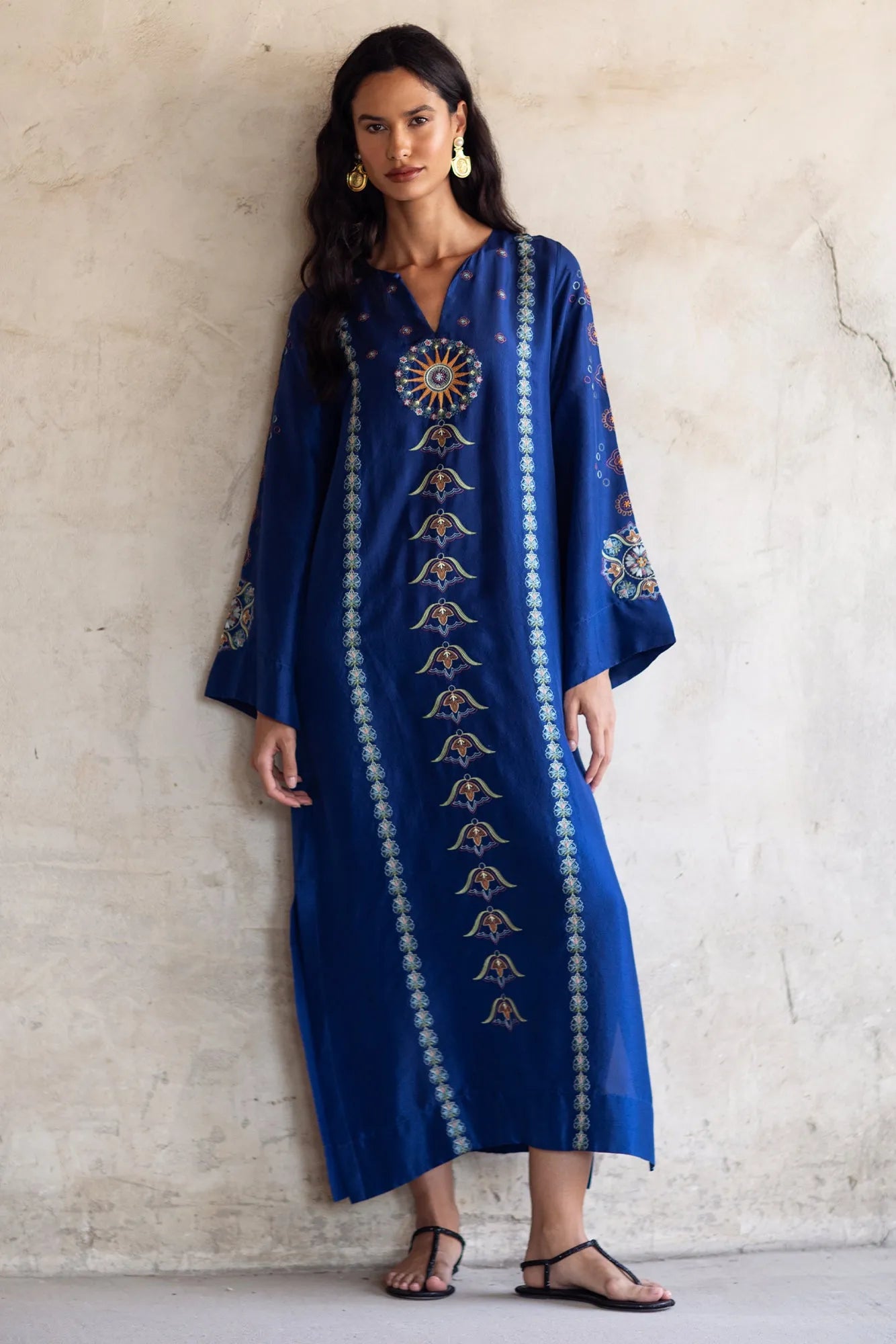 Woman wearing a blue embroidered dress against a light background