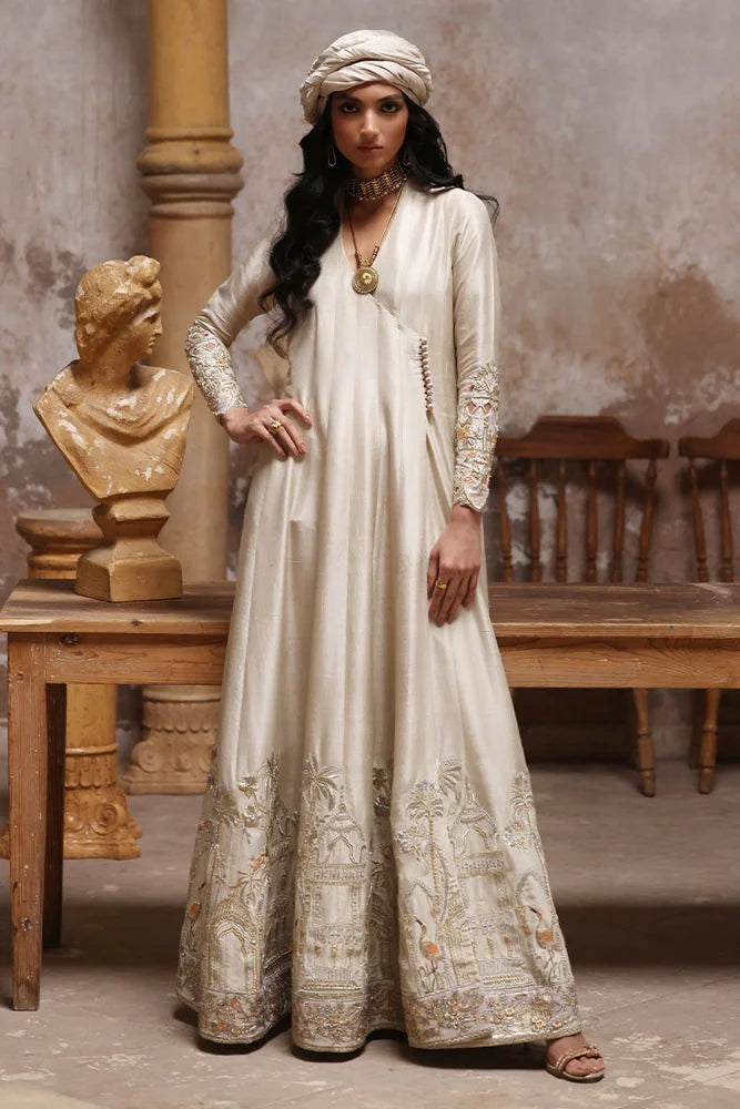 Woman in a long, ornate dress standing in a rustic interior setting.