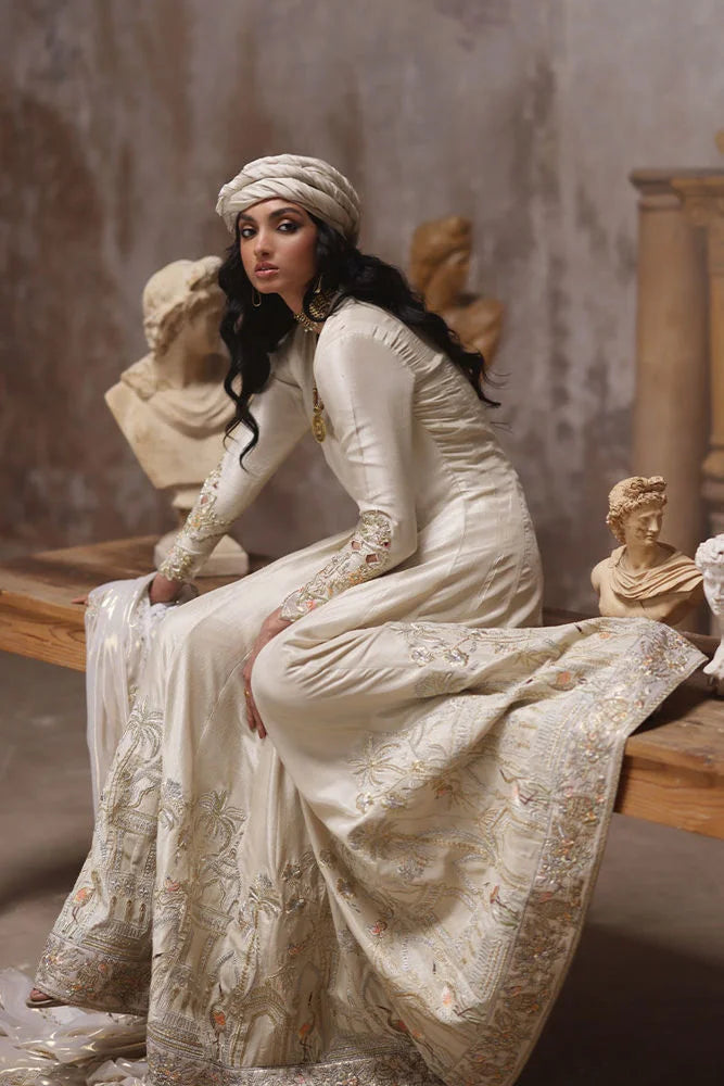 Woman in a white dress sitting among classical sculptures