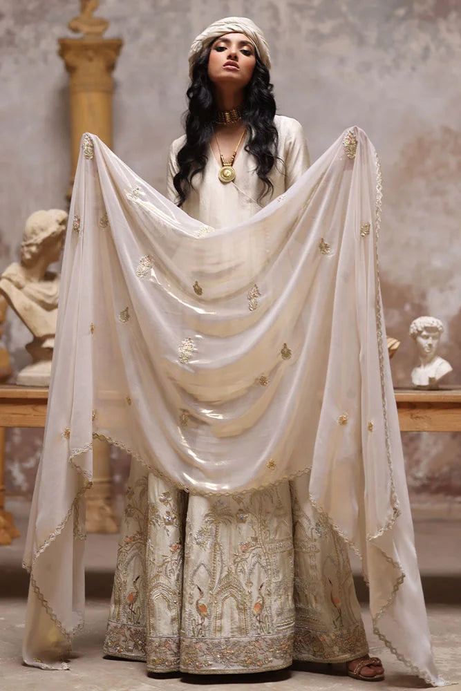 Woman in a traditional outfit with a white dupatta in an indoor setting