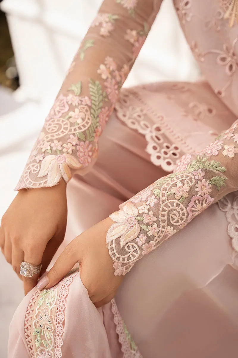 Close-up of a person wearing a light pink embroidered outfit with floral patterns.