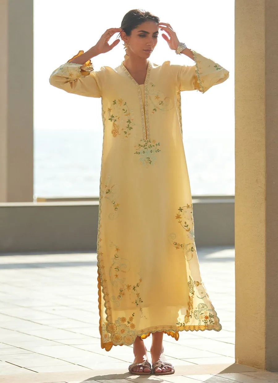 Woman wearing a yellow embroidered dress on a bright outdoor setting