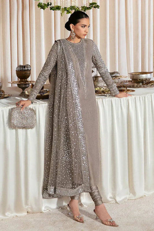 Woman in a silver and gray traditional outfit standing in front of a decorated table.