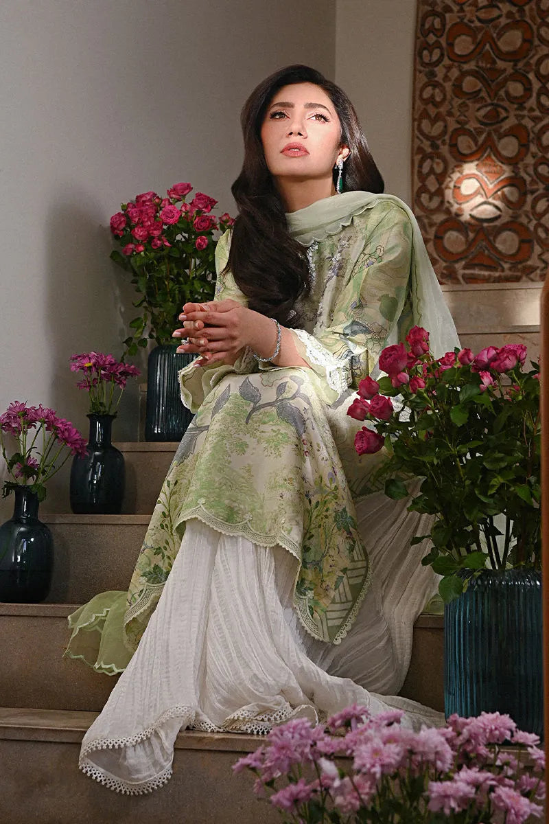 Woman in a light green and white traditional outfit sitting among flowers indoors.