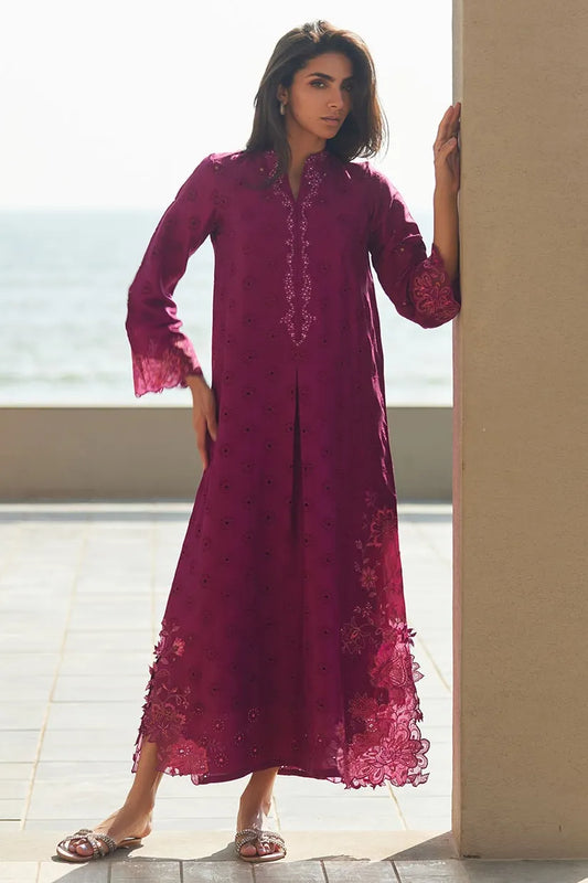 Woman wearing a burgundy lace dress standing by a window with a view of water.
