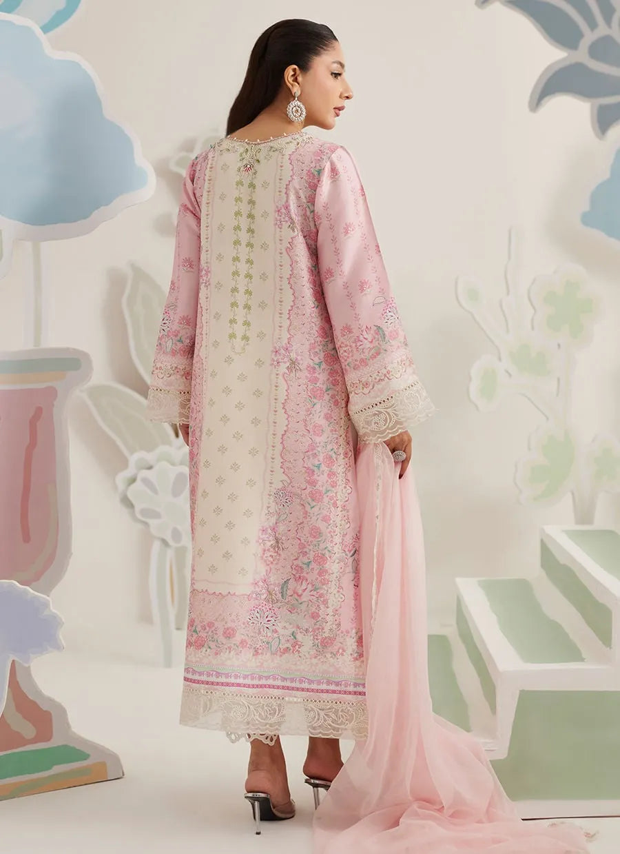 Woman wearing a pink and white embroidered traditional outfit with a matching dupatta against a decorative wall.