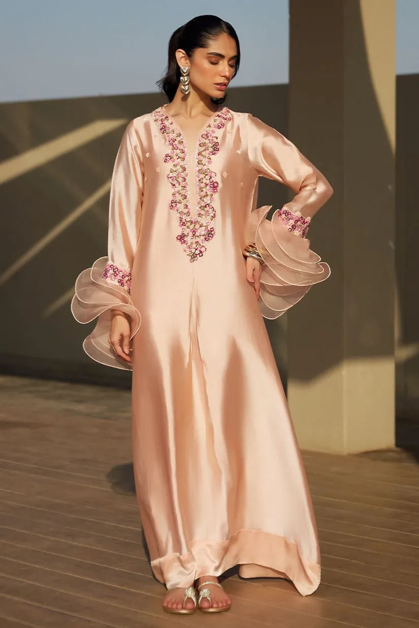 Woman wearing a light pink embroidered dress on a rooftop.