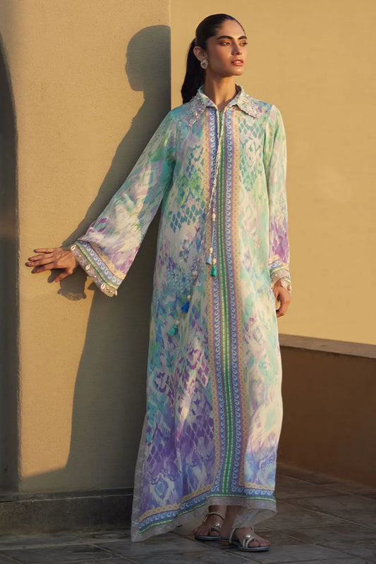 Woman wearing a long, patterned dress against a beige wall.